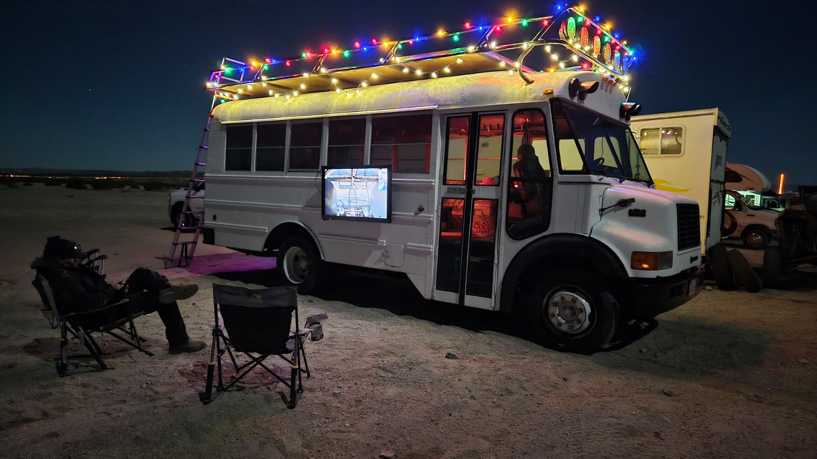 Team members gathered outside the support bus watching the live stream on a screen during a race